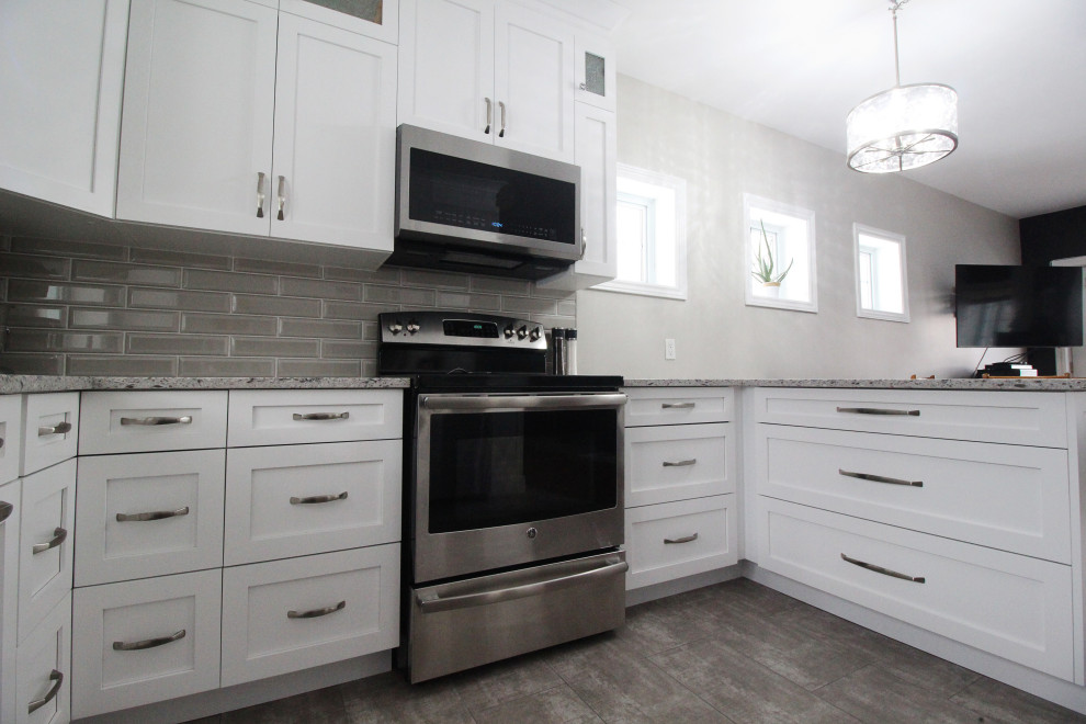U-shaped kitchen photo with shaker cabinets, white cabinets, quartzite countertops, gray backsplash, subway tile backsplash, a peninsula and gray countertops