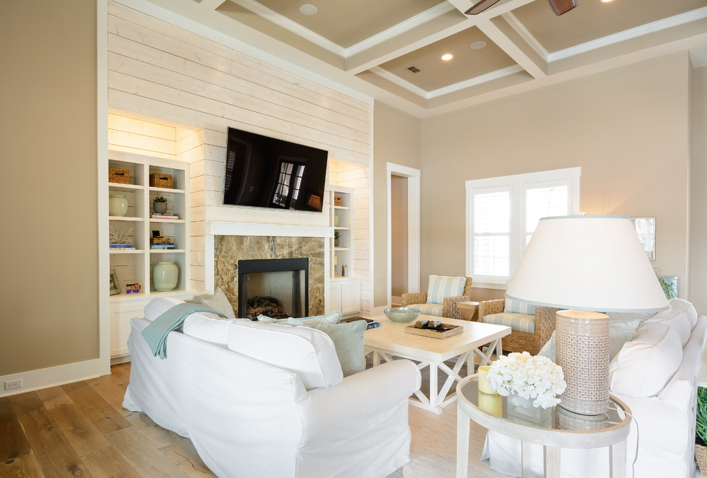 Inspiration for a large beach style open concept family room in Jacksonville with beige walls, light hardwood floors, a standard fireplace, a stone fireplace surround and a wall-mounted tv.