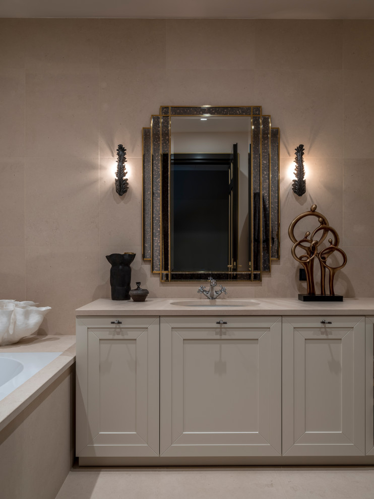 Photo of a mid-sized transitional master bathroom in Moscow with recessed-panel cabinets, beige cabinets, an undermount tub, a shower/bathtub combo, a wall-mount toilet, beige tile, limestone, beige walls, limestone floors, an undermount sink, limestone benchtops, beige floor, an open shower and beige benchtops.
