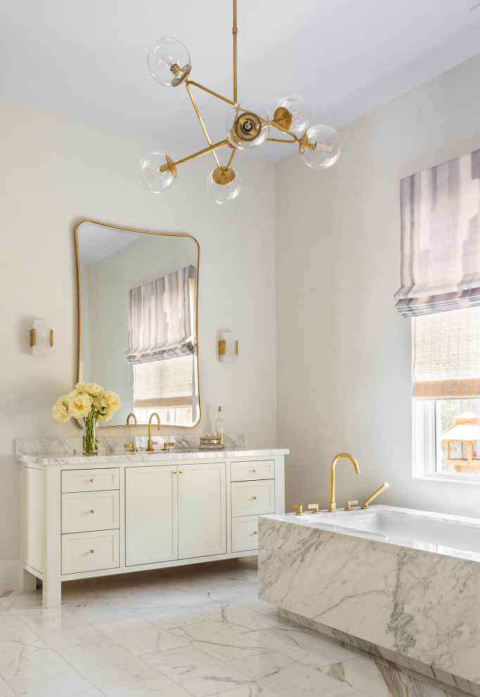 This is an example of a transitional master bathroom in Houston with recessed-panel cabinets, white cabinets, a freestanding tub, white walls, marble floors, an undermount sink, marble benchtops, white floor, white benchtops, a single vanity and a built-in vanity.