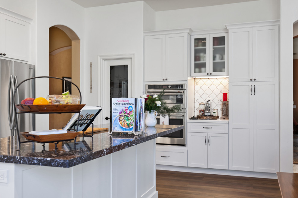Inspiration for a large transitional u-shaped vinyl floor and brown floor open concept kitchen remodel in San Diego with shaker cabinets, white cabinets, quartz countertops, white backsplash, porcelain backsplash, stainless steel appliances, an island and white countertops