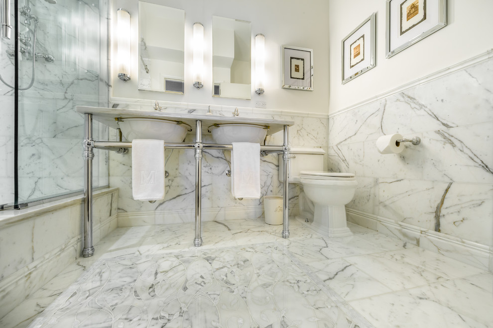 This is an example of a mid-sized contemporary master bathroom in New York with an undermount sink, marble benchtops, an alcove shower, a one-piece toilet, white tile, stone tile, white walls and marble floors.