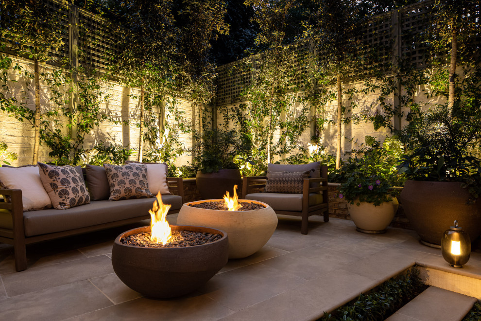 Small traditional back patio in London with a fireplace and natural stone paving.