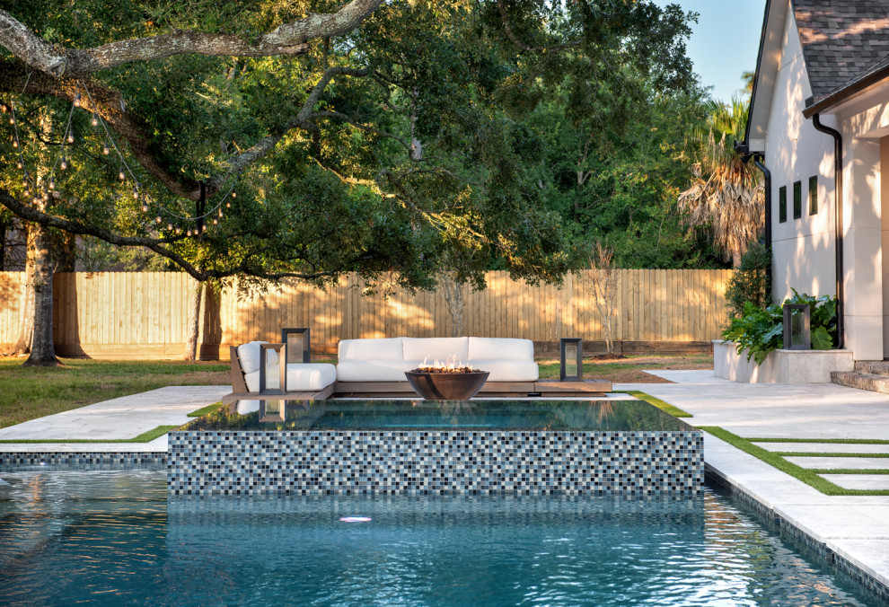 Diseño de piscina romántica grande rectangular en patio trasero con adoquines de piedra natural
