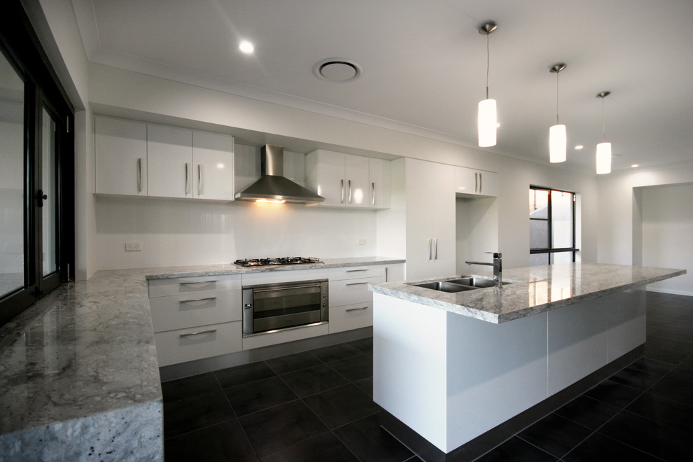 Photo of a large contemporary galley eat-in kitchen in Brisbane with an undermount sink, flat-panel cabinets, yellow cabinets, granite benchtops, white splashback, glass sheet splashback, white appliances, ceramic floors and multiple islands.