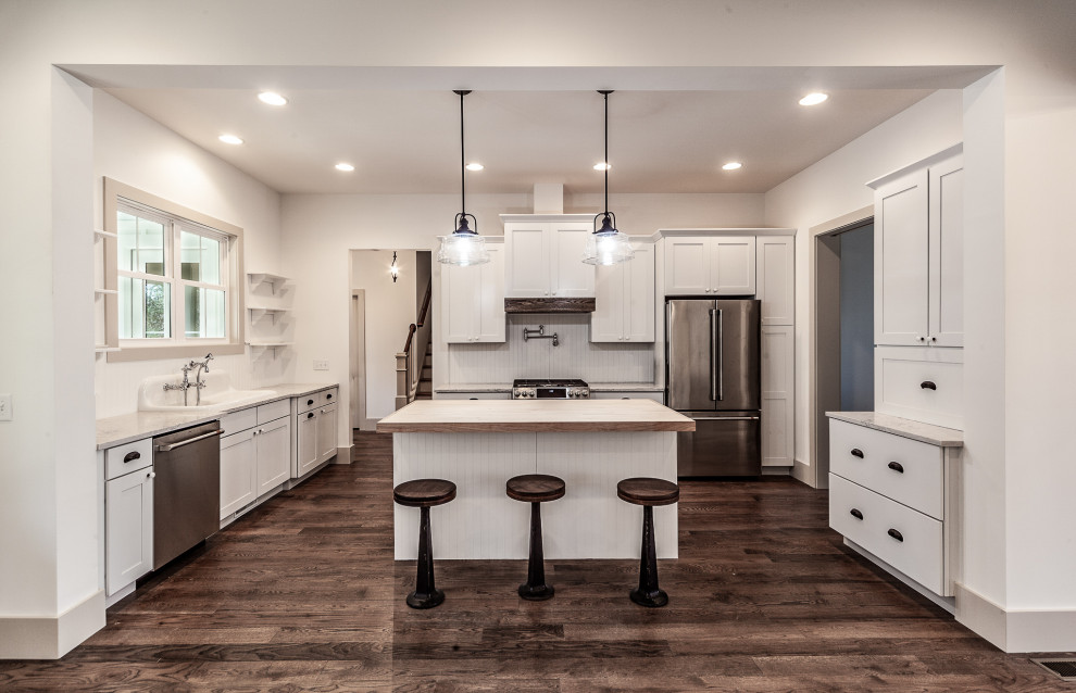 Design ideas for a mid-sized country u-shaped open plan kitchen in Other with a farmhouse sink, flat-panel cabinets, white cabinets, quartzite benchtops, white splashback, timber splashback, stainless steel appliances, dark hardwood floors, with island, brown floor and white benchtop.