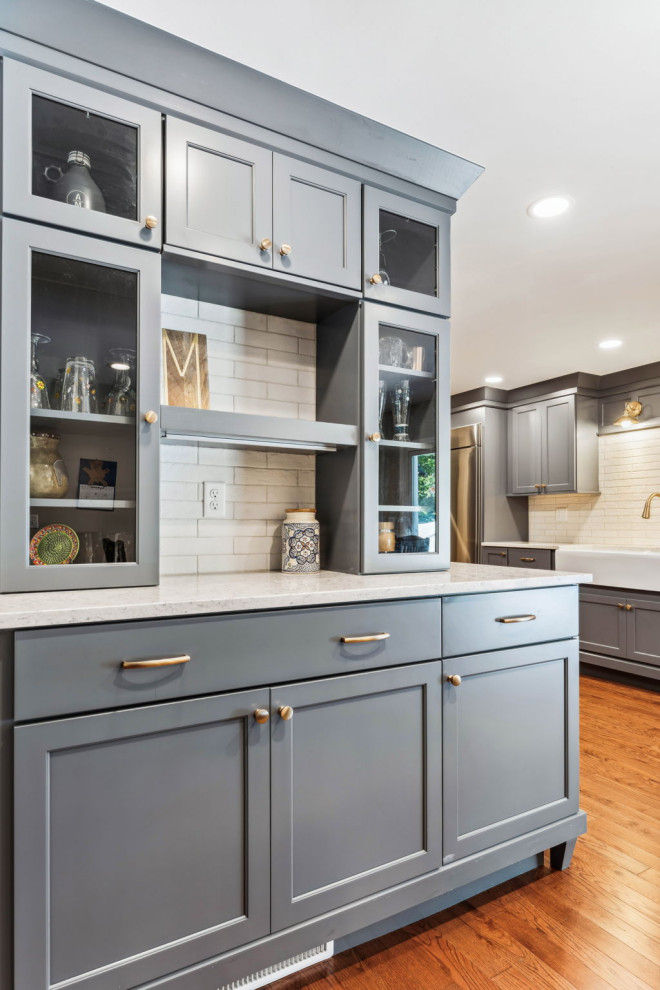 Inspiration for a small timeless l-shaped medium tone wood floor and brown floor eat-in kitchen remodel in Columbus with a farmhouse sink, shaker cabinets, blue cabinets, quartz countertops, white backsplash, porcelain backsplash, stainless steel appliances, no island and white countertops