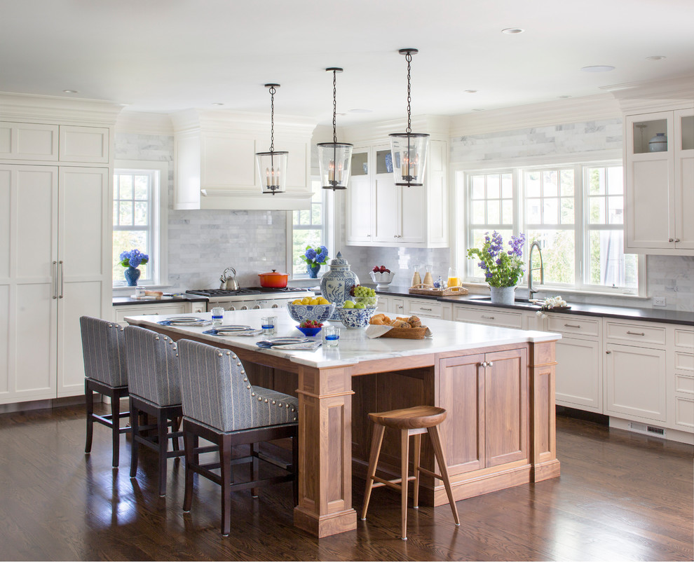 Inspiration for a transitional l-shaped medium tone wood floor and brown floor kitchen remodel in New York with shaker cabinets, white cabinets, gray backsplash, an island and black countertops