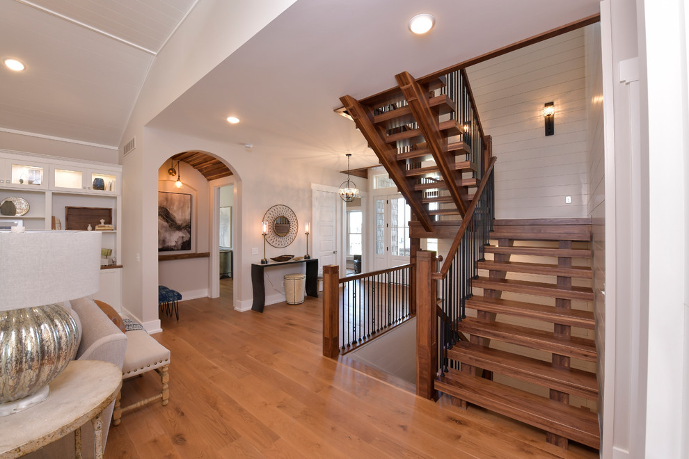 Traditional wood u-shaped staircase with open risers, mixed railing and planked wall panelling.