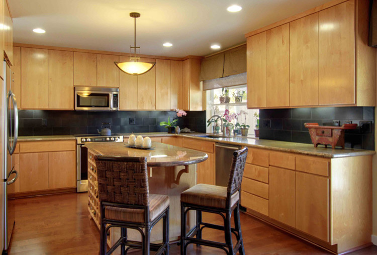 This is an example of a mid-sized asian u-shaped eat-in kitchen in Sacramento with an undermount sink, flat-panel cabinets, medium wood cabinets, granite benchtops, black splashback, ceramic splashback, stainless steel appliances, dark hardwood floors and with island.