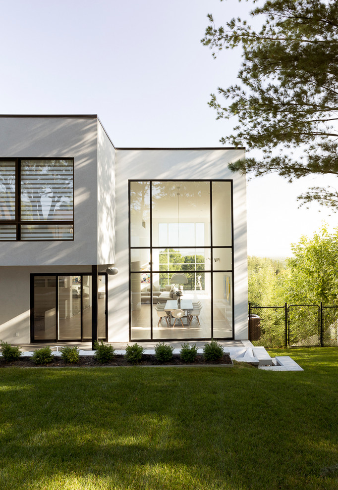 Inspiration for a large contemporary two-storey white house exterior in Montreal with a flat roof and mixed siding.
