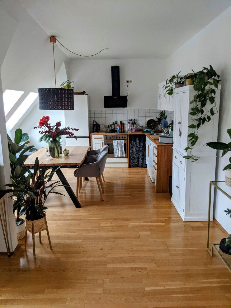 Foto di una sala da pranzo aperta verso la cucina country di medie dimensioni con pareti bianche, pavimento in legno massello medio, pavimento marrone e soffitto ribassato