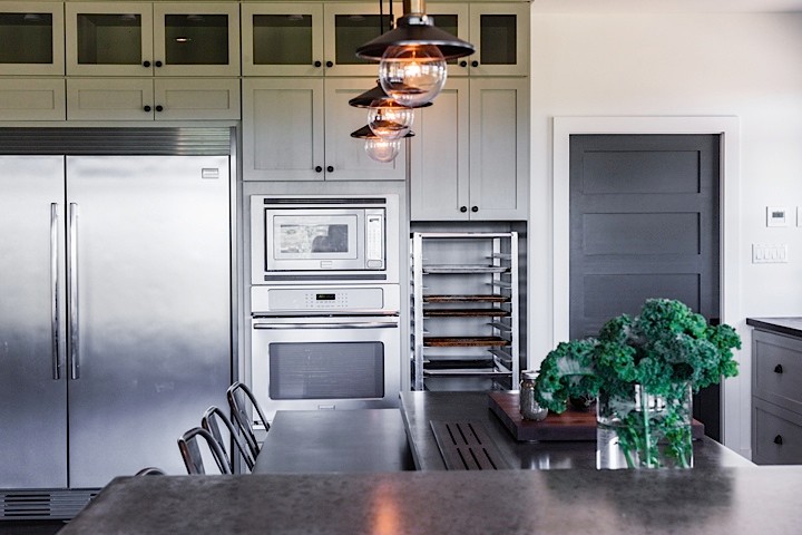 Example of a large mountain style u-shaped medium tone wood floor eat-in kitchen design with an integrated sink, shaker cabinets, green cabinets, concrete countertops, white backsplash, subway tile backsplash, stainless steel appliances and an island