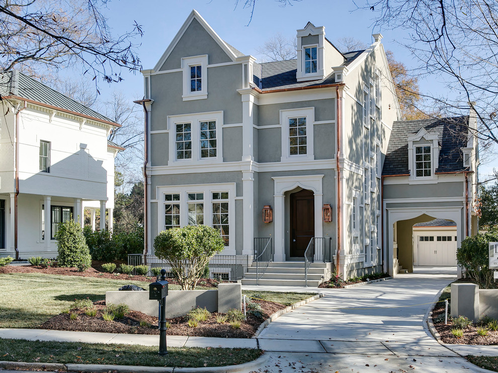 Photo of a transitional stucco house exterior in Raleigh with a shingle roof.