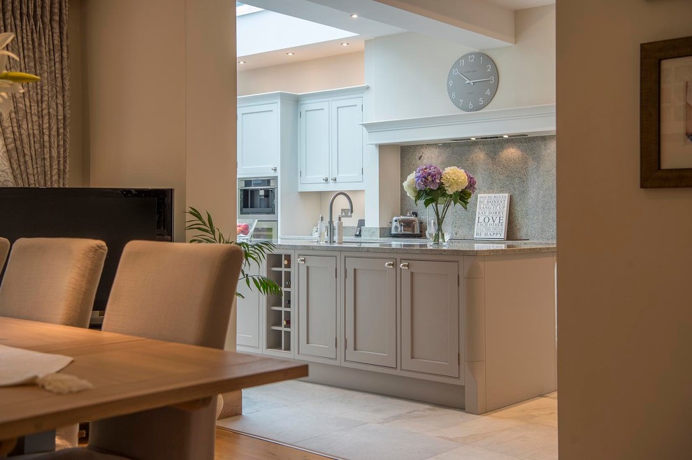 This is an example of a large traditional l-shaped open plan kitchen in Other with an undermount sink, shaker cabinets, beige cabinets, granite benchtops, multi-coloured splashback, stainless steel appliances and with island.