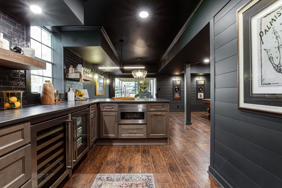Large contemporary walk-out basement in Atlanta with a home bar, black walls, vinyl floors, a standard fireplace, a brick fireplace surround, brown floor and planked wall panelling.