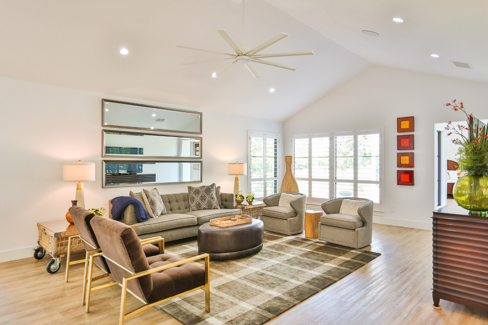 This is an example of a large midcentury open concept living room in Austin with white walls, light hardwood floors, no fireplace, a freestanding tv and beige floor.