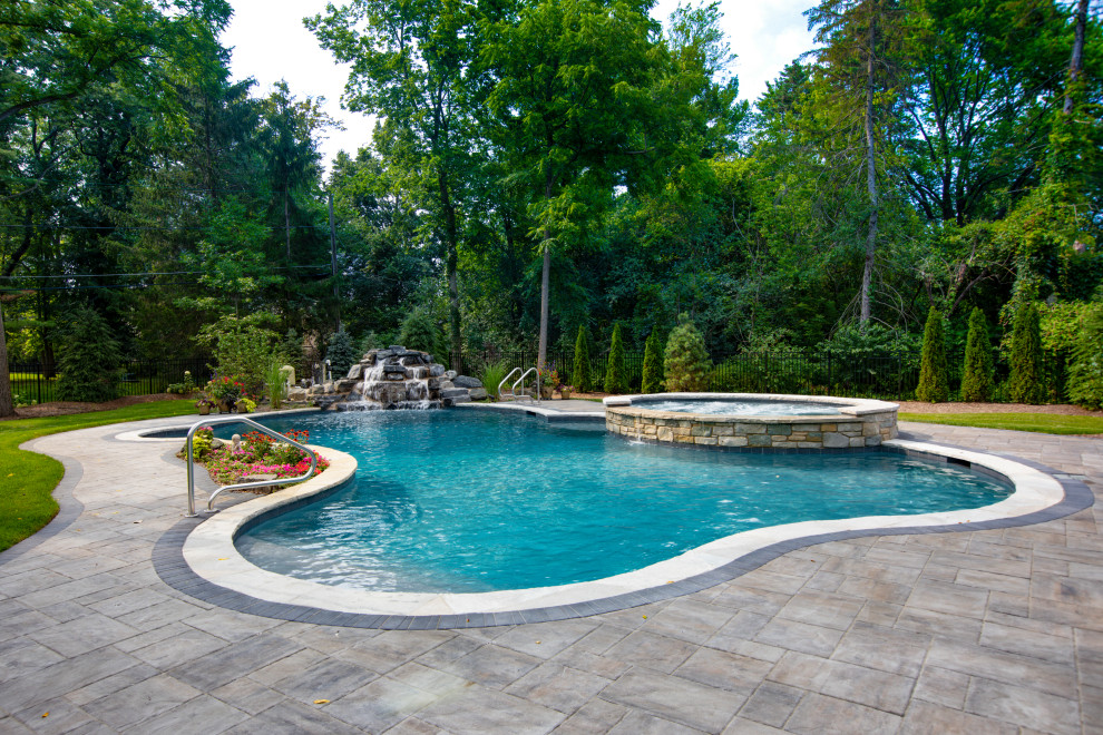 Esempio di una piscina naturale classica personalizzata di medie dimensioni e dietro casa con una vasca idromassaggio e pavimentazioni in pietra naturale