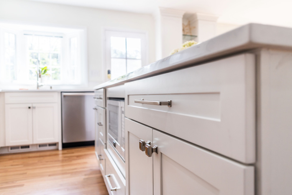 Eat-in kitchen - mid-sized transitional l-shaped light wood floor and brown floor eat-in kitchen idea in Baltimore with an undermount sink, shaker cabinets, white cabinets, quartz countertops, white backsplash, marble backsplash, stainless steel appliances, an island and white countertops