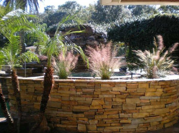 Inspiration for a mid-sized partial sun backyard stone retaining wall landscape in Orlando.