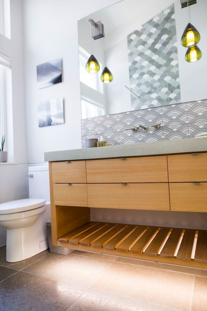Photo of a small modern 3/4 wet room bathroom in Other with flat-panel cabinets, light wood cabinets, a freestanding tub, a one-piece toilet, beige tile, ceramic tile, beige walls, limestone floors, an integrated sink, concrete benchtops, grey floor, an open shower and grey benchtops.
