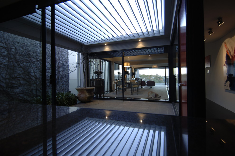 This is an example of a contemporary courtyard patio in Sydney with a roof extension.