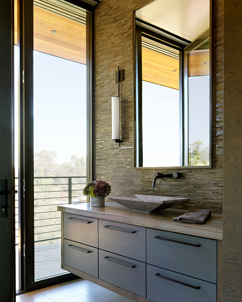 This is an example of a mid-sized modern 3/4 bathroom in San Francisco with a vessel sink, grey cabinets, quartzite benchtops, beige tile, flat-panel cabinets, a freestanding tub, a corner shower, a two-piece toilet, slate, beige walls, marble floors, beige floor and a hinged shower door.