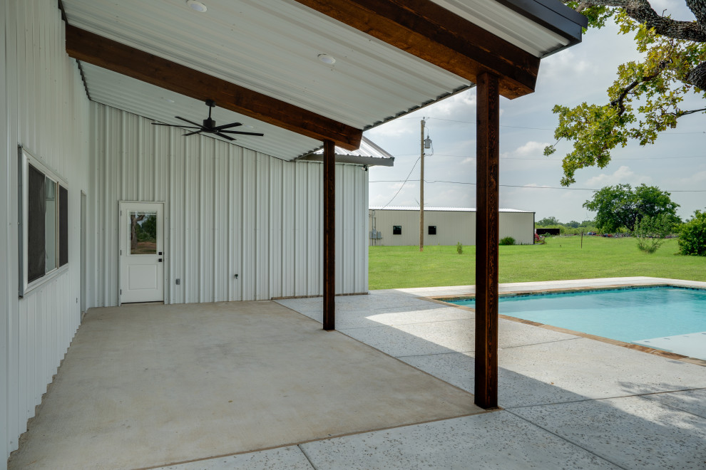 Esempio di un portico country di medie dimensioni e dietro casa con lastre di cemento e un tetto a sbalzo