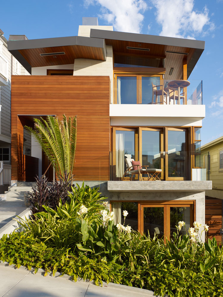 This is an example of a mid-sized tropical three-storey house exterior in Los Angeles with wood siding and a metal roof.