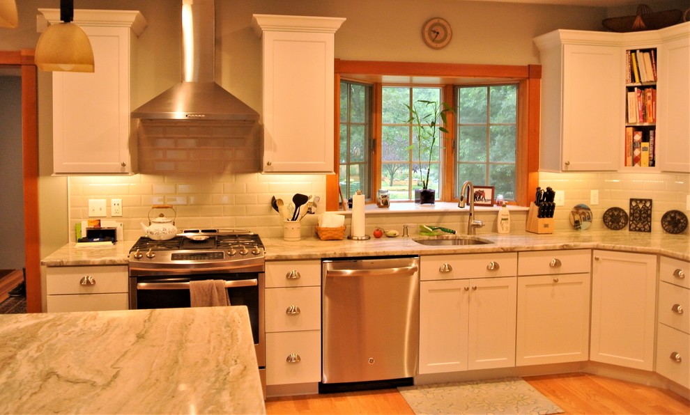 Inspiration for a transitional light wood floor kitchen remodel in Boston with an undermount sink, shaker cabinets, white cabinets, quartzite countertops, white backsplash, subway tile backsplash, stainless steel appliances and an island