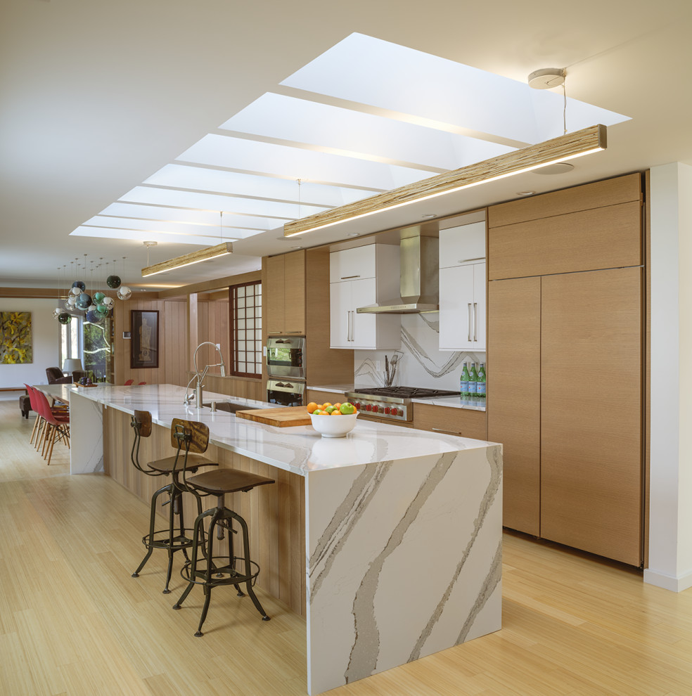 This is an example of a large modern galley eat-in kitchen in Wilmington with an undermount sink, flat-panel cabinets, beige cabinets, marble benchtops, white splashback, marble splashback, stainless steel appliances, bamboo floors, with island, beige floor, white benchtop and recessed.