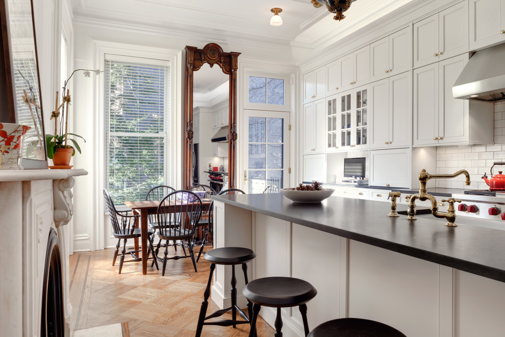 Elegant medium tone wood floor eat-in kitchen photo in New York with a farmhouse sink, recessed-panel cabinets, white backsplash, subway tile backsplash and an island