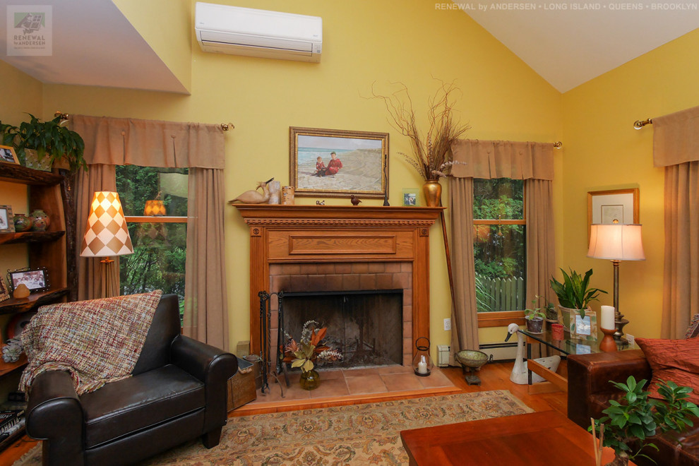 This is an example of a medium sized enclosed living room in New York with yellow walls, medium hardwood flooring, a standard fireplace, a wooden fireplace surround and a vaulted ceiling.