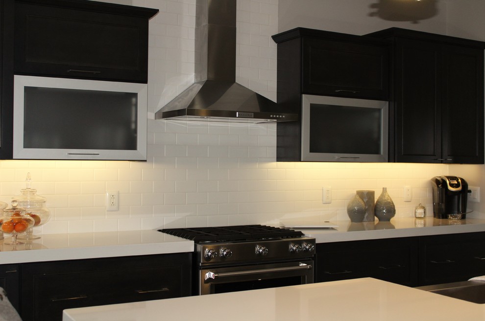 Inspiration for a mid-sized transitional medium tone wood floor kitchen remodel in Chicago with a farmhouse sink, recessed-panel cabinets, quartzite countertops, white backsplash, ceramic backsplash, stainless steel appliances and an island