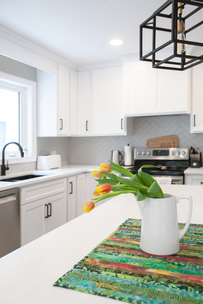 Transitional gray floor kitchen photo with an undermount sink, shaker cabinets, white cabinets, quartz countertops, gray backsplash, ceramic backsplash, stainless steel appliances, an island and white countertops