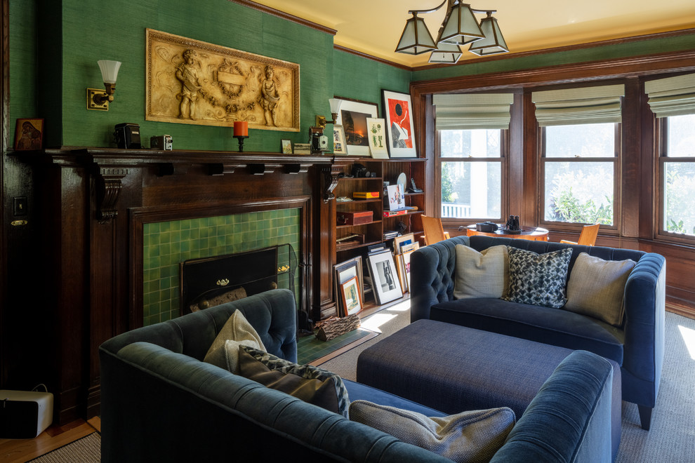 Traditional family room in New York with a library, green walls, medium hardwood floors, a standard fireplace, a tile fireplace surround and brown floor.