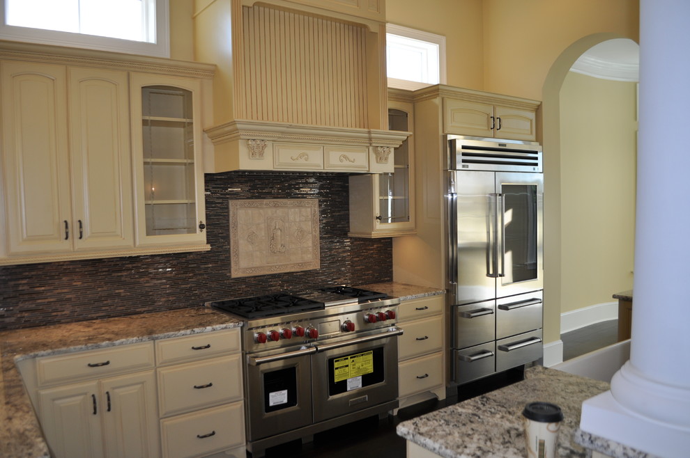Open concept kitchen - mid-sized transitional l-shaped dark wood floor and brown floor open concept kitchen idea with an undermount sink, raised-panel cabinets, yellow cabinets, granite countertops, gray backsplash, matchstick tile backsplash, stainless steel appliances and an island