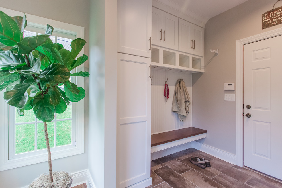 Inspiration for a mid-sized transitional galley utility room in Cincinnati with shaker cabinets, white cabinets, grey walls, linoleum floors, a side-by-side washer and dryer and brown floor.