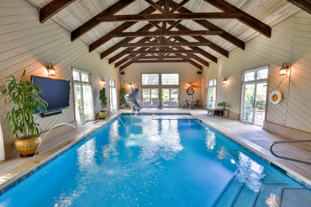 Mid-sized traditional indoor rectangular lap pool in Chicago with a pool house and natural stone pavers.