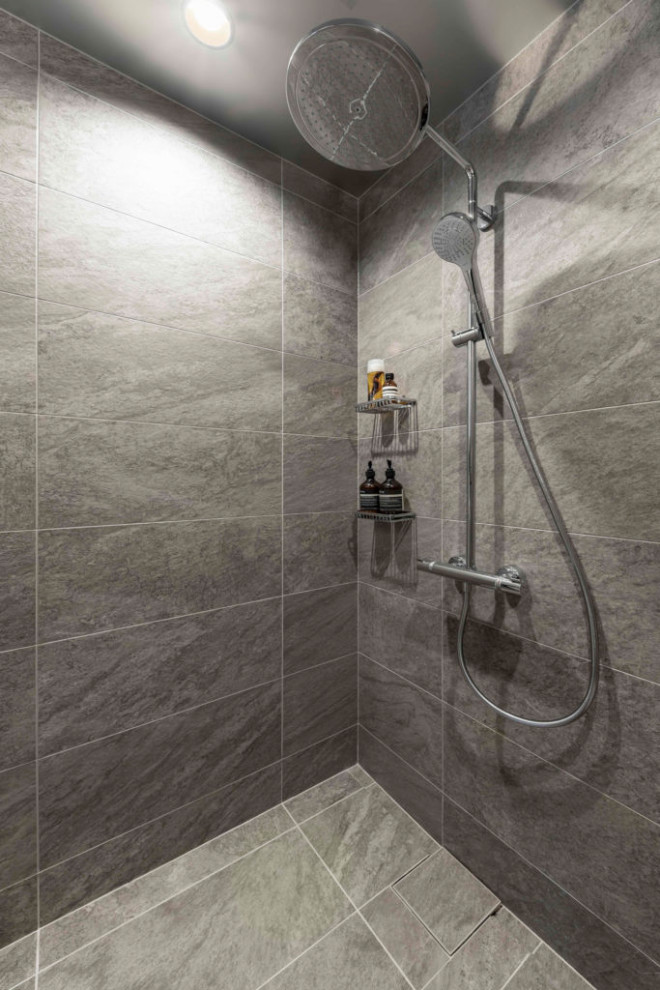 Modern inredning av ett litet badrum med dusch, med grå kakel, porslinskakel, grå väggar, klinkergolv i porslin, grått golv och dusch med gångjärnsdörr