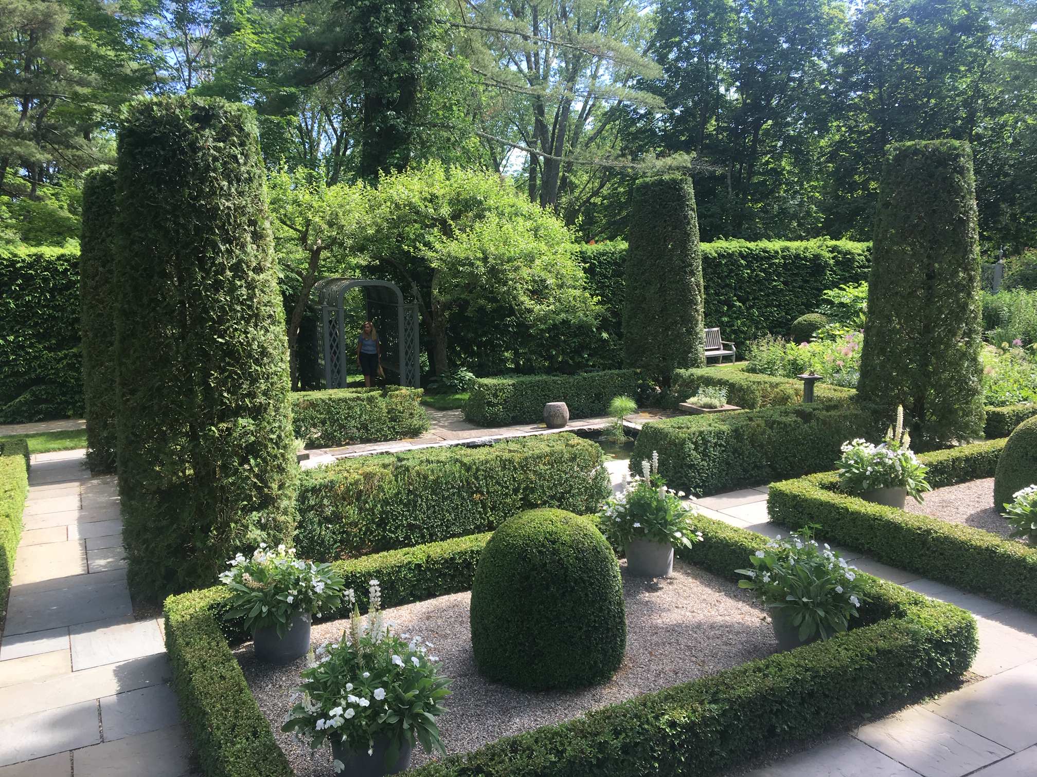 Formal Boxwood Gardens, Arborvitae sheered trees and  flower beds all planted with white. The inside of the beds is pea gravel and whistera is above the lady in the archway. Private Garden. Photo by P