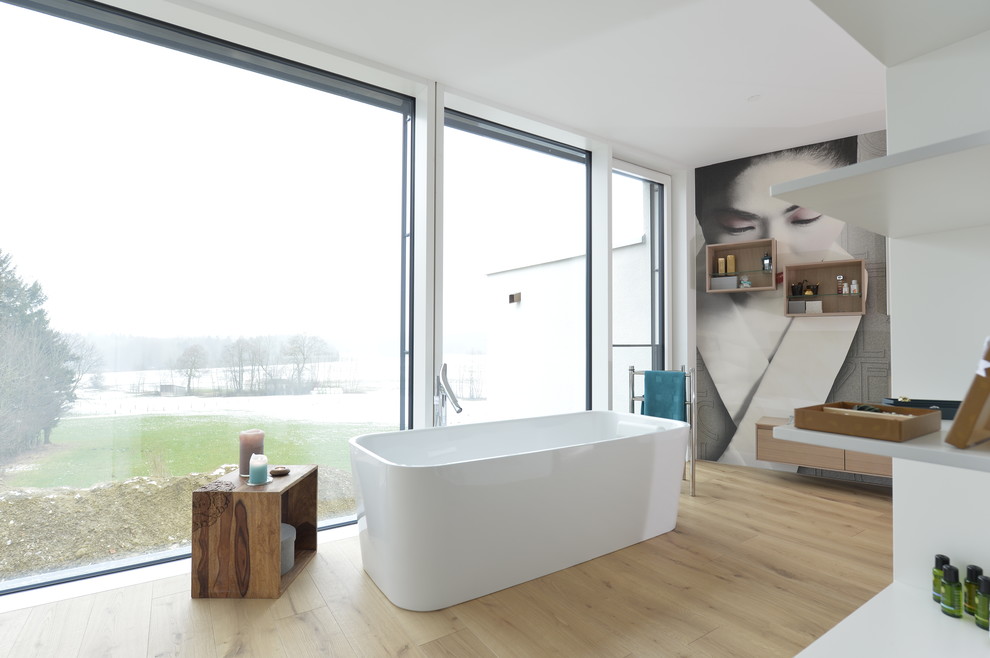 This is an example of an expansive asian master bathroom in Munich with flat-panel cabinets, light wood cabinets, a freestanding tub, a curbless shower, white walls, light hardwood floors, a vessel sink, brown floor and an open shower.