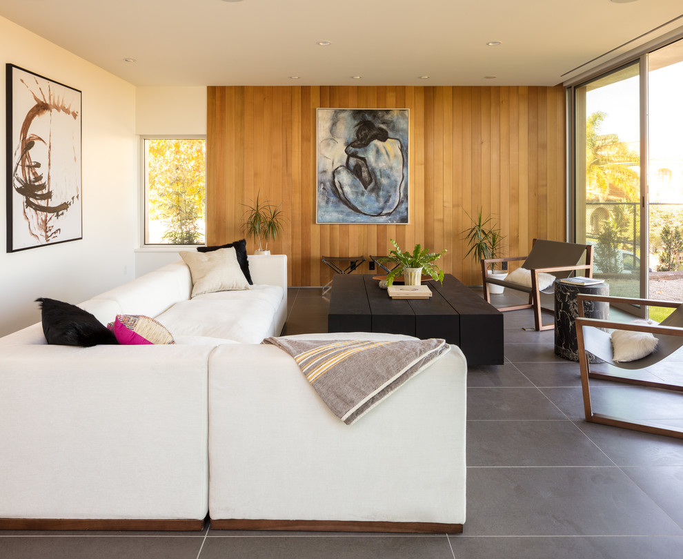 This is an example of a mid-sized modern open concept living room in Los Angeles with white walls, ceramic floors, no fireplace, a concealed tv and grey floor.