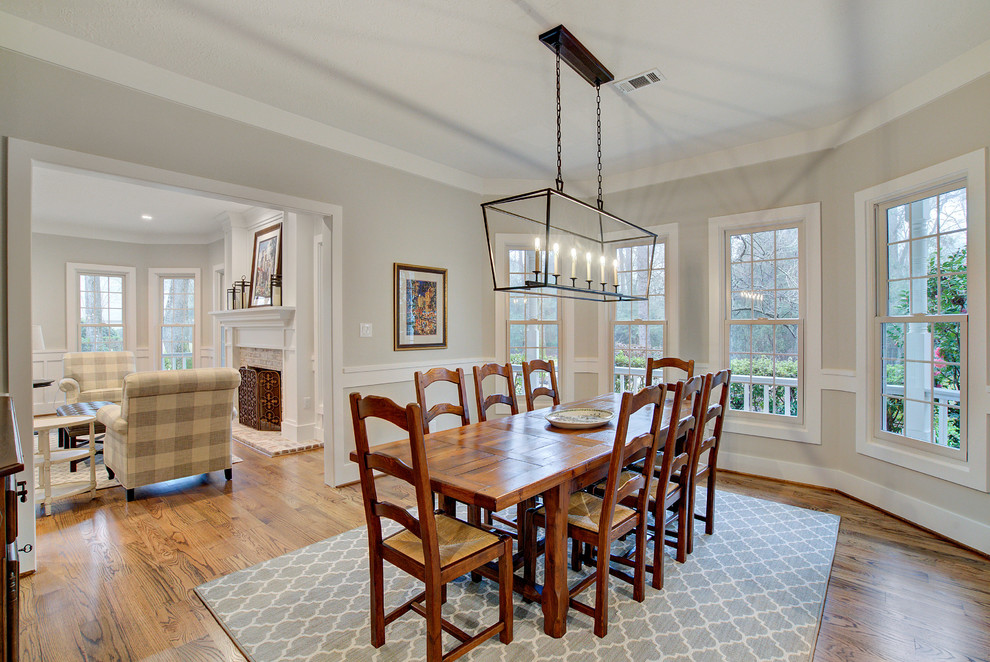 This is an example of a transitional dining room in Houston with medium hardwood floors, brown floor and grey walls.