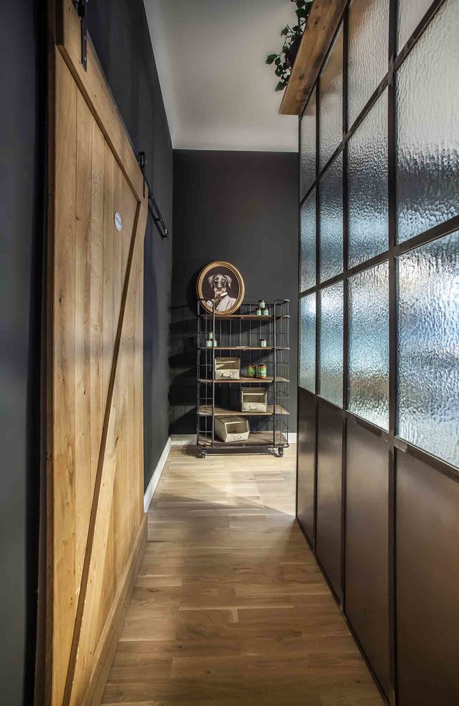 Inspiration for a mid-sized industrial hallway in Berlin with light hardwood floors, brown floor and black walls.