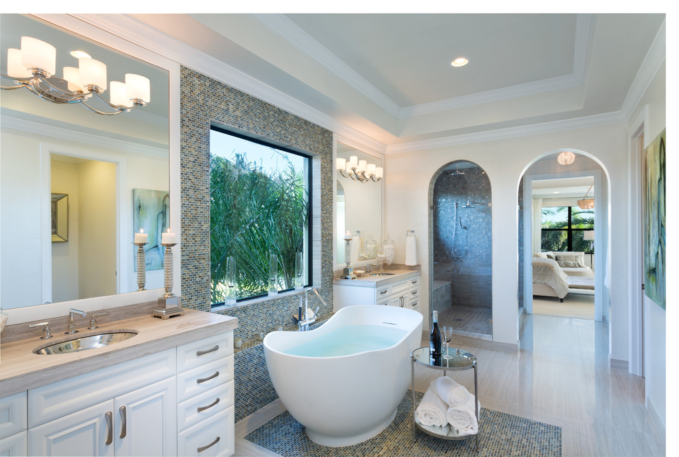 Eclectic master bathroom in Miami with raised-panel cabinets, white cabinets, a freestanding tub, a corner shower, a one-piece toilet, gray tile, stone tile, grey walls, an undermount sink and marble benchtops.
