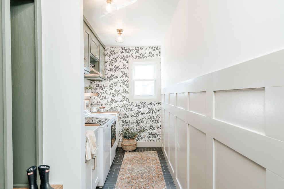 Mid-sized minimalist single-wall ceramic tile, gray floor and wallpaper utility room photo in Detroit with a farmhouse sink, shaker cabinets, green cabinets, wood countertops, white backsplash, cement tile backsplash, beige walls, a side-by-side washer/dryer and brown countertops
