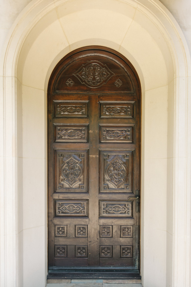 Front door - limestone floor and beige floor front door idea in Los Angeles with beige walls and a dark wood front door
