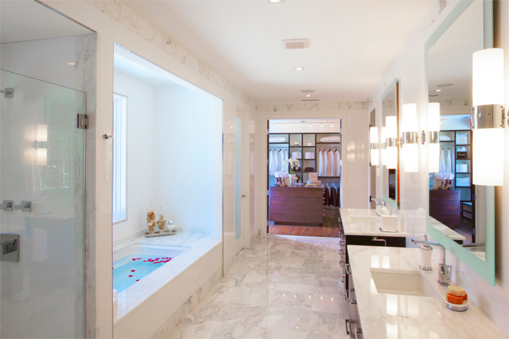 Expansive country bathroom in New York with a drop-in sink, dark wood cabinets, marble benchtops, a drop-in tub, a wall-mount toilet, white tile, glass tile, white walls and marble floors.