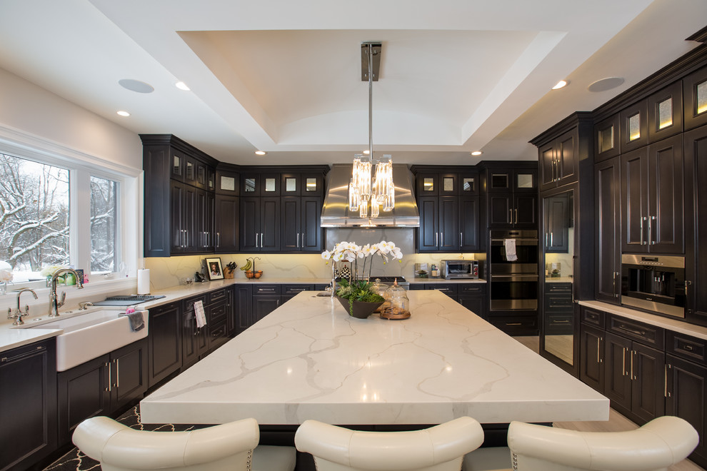 Photo of a transitional u-shaped separate kitchen in Detroit with a farmhouse sink, recessed-panel cabinets, black cabinets, beige splashback, panelled appliances, ceramic floors, with island and black floor.